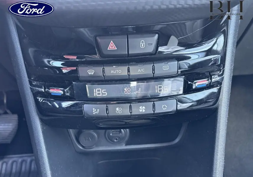 Console centrale noire avec commandes climatisation automatique bi-zone et prises 12V dans un Ford, vue rapprochée frontale.