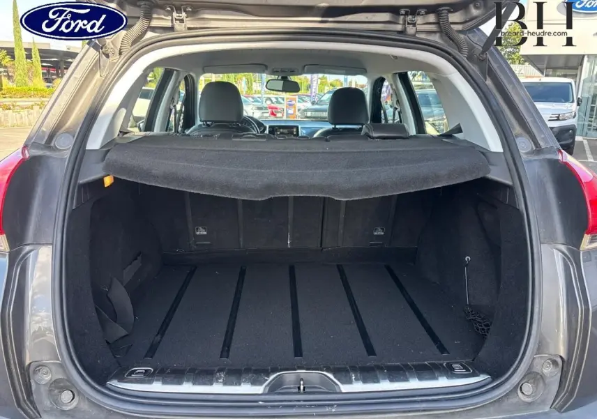 Coffre ouvert vu de l'arrière d'un Peugeot 2008 Spirit Grey avec cache-bagages et banquette arrière visible.