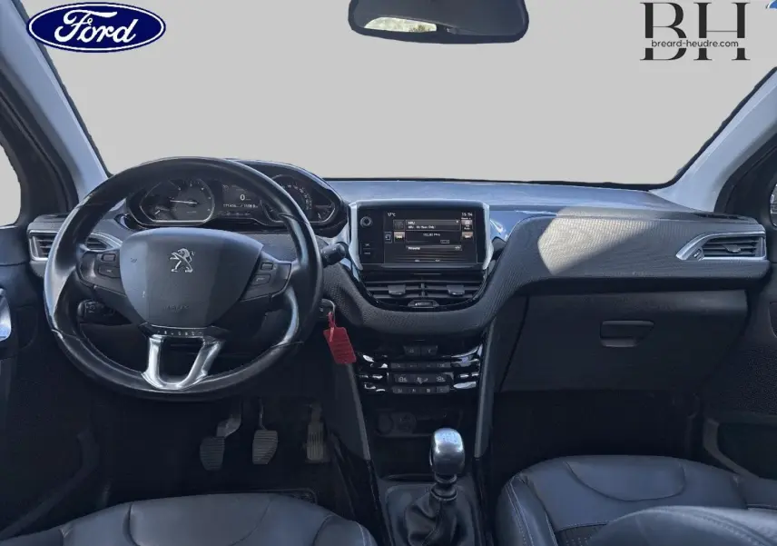 Vue intérieure avant du Peugeot 2008 2015 avec tableau de bord noir et volant cuir multifonction.