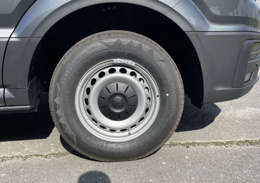 Gros plan sur la roue avant gauche du Volkswagen Crafter Van gris Indium, mettant en valeur la jante acier et le pneu robuste.