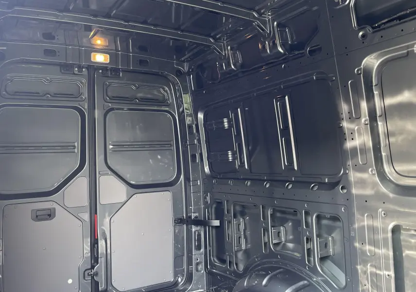 Vue intérieure arrière du Volkswagen Crafter van gris Indium montrant la cloison avec vitre fixe et l'espace de chargement métallique.