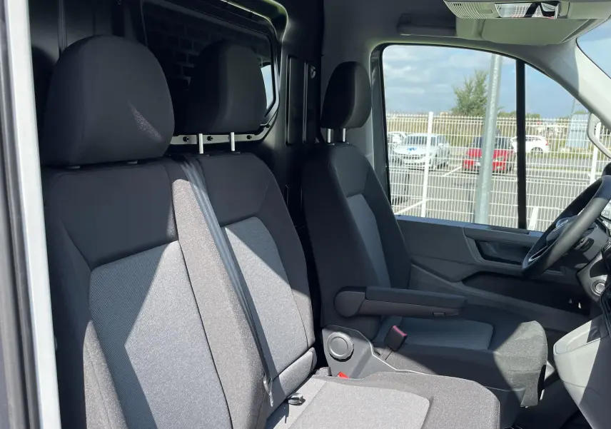 Intérieur du Volkswagen Crafter 35 L3H3 gris Indium, vue côté droit sur les sièges avant et la cloison vitrée.