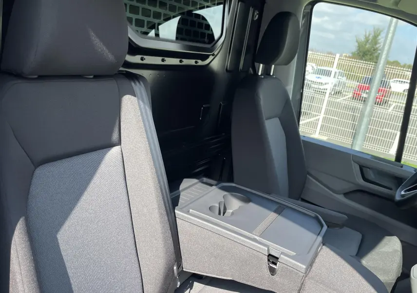 Vue intérieure côté conducteur du Volkswagen Crafter Van gris Indium, montrant les sièges et la cloison avec vitre fixe.