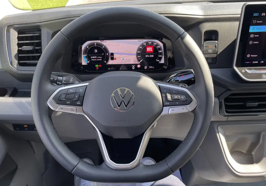 Vue rapprochée du volant noir et du tableau de bord numérique du Volkswagen Crafter Van gris Indium avec écran tactile.