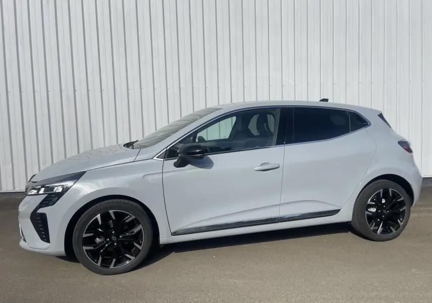 Renault Clio V TCE 90 gris Rafale vue de profil côté gauche avec jantes alliage noires et contour fenêtres aluminium.