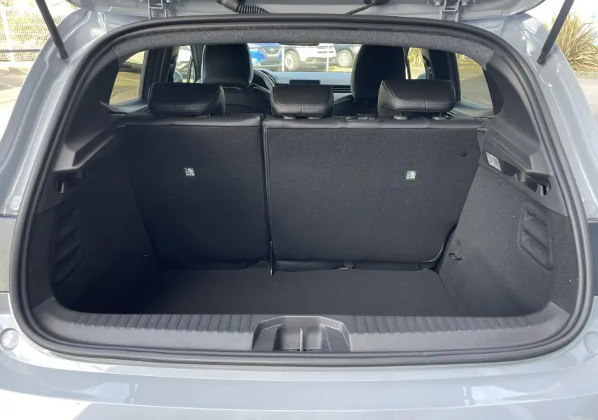 Coffre ouvert vu de l'arrière d'une Renault Clio Gris Rafale, montrant l'espace de chargement et les sièges arrière.