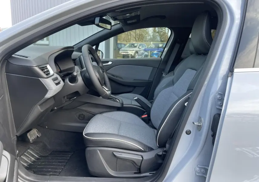 Vue côté gauche de l'intérieur de la Renault Clio Gris Rafale 2025, sièges tissu gris et volant multifonction.