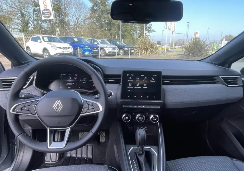 Vue intérieure du tableau de bord et volant de la Renault Clio 2025 avec écran tactile et sellerie gris foncé.