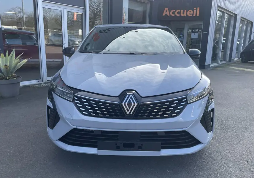 Renault Clio 2025 gris Rafale vue de face, avec calandre noire et logo Renault centré, stationnée devant un bâtiment.