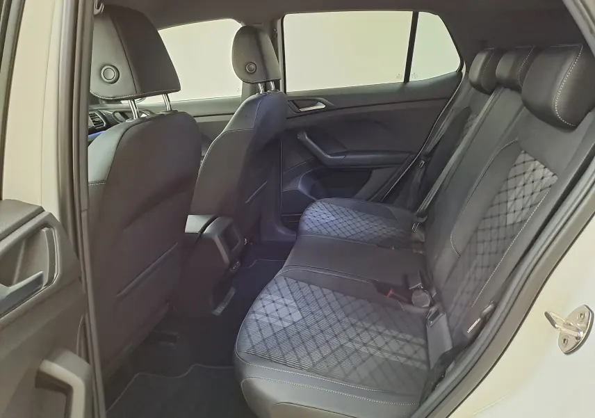 Vue intérieure arrière côté droit du Volkswagen T-Cross blanc, mettant en valeur les sièges arrière en tissu noir à motif losange.