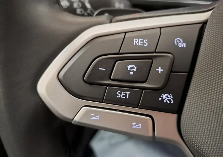 Gros plan sur les commandes de régulateur de vitesse au volant du Volkswagen T-Cross 2025 blanc pur R-Line Edition.