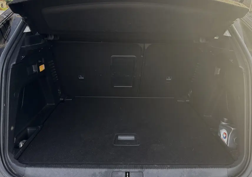 Coffre ouvert d'un Peugeot 3008 II 1.5 BlueHDi 130 Active 2019, vue intérieure avec revêtement noir et bidon d'huile.
