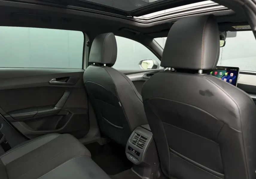 Vue arrière de l'habitacle noir cuir de la CUPRA LEON ST 1.5 e-TSI 150 DSG avec toit ouvrant panoramique et commandes climatisation.