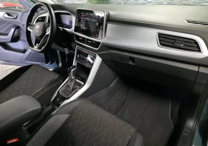 Intérieur avant du Volkswagen T-Roc bleu, vue côté conducteur, tableau de bord digital et sellerie noire.