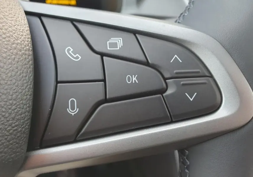 Gros plan sur les commandes multifonctions au volant du Dacia Bigster 2026, boutons noirs avec icônes blanches.