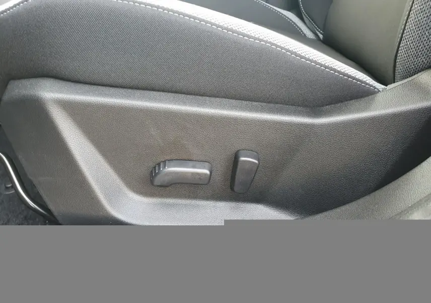 Gros plan sur les commandes de réglage lombaire du siège conducteur du Dacia Bigster noir Perla, intérieur tissu gris.