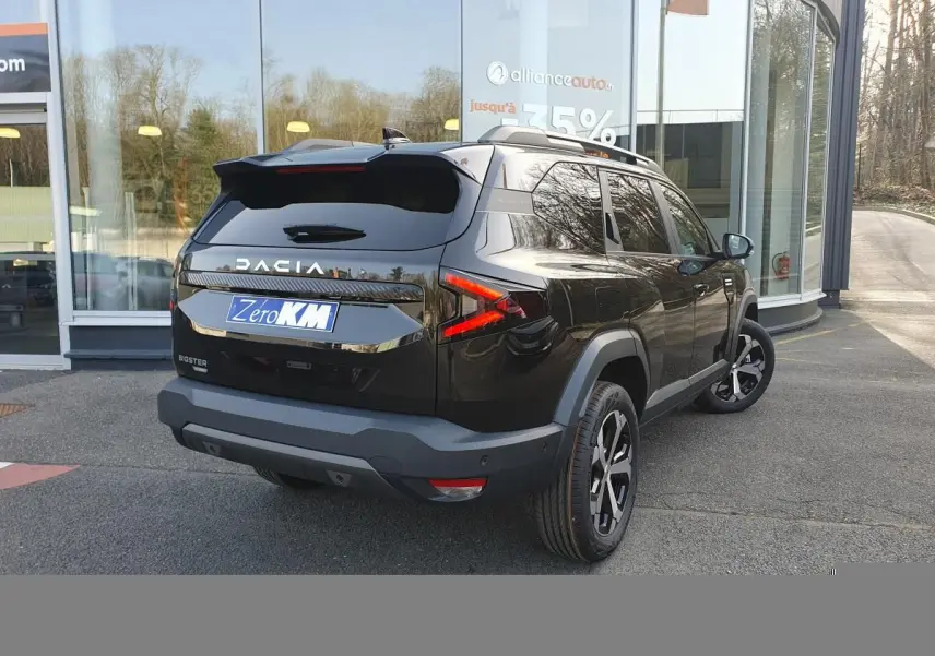 Vue 3/4 arrière droite du Dacia Bigster noir Perla avec jantes alliage 18” diamantées et barres de toit longitudinales.