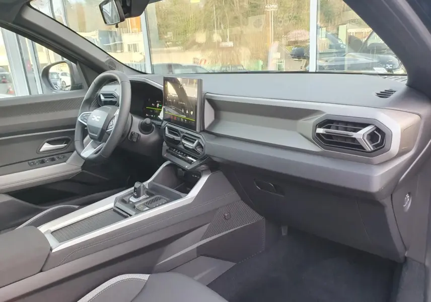 Intérieur du Dacia Bigster 2026 vu côté passager, tableau de bord moderne avec écran central tactile.