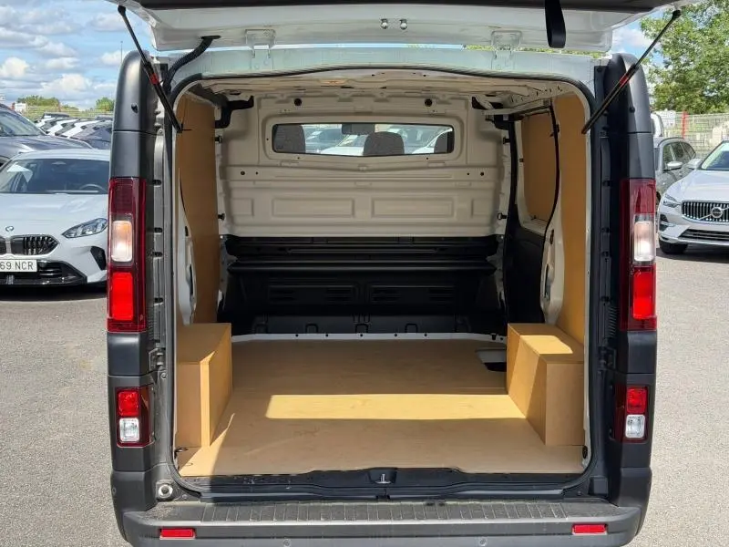 Vue arrière ouverte du Renault Trafic Fourgon blanc glacier 2024, montrant l'espace de chargement vide avec cloison pleine.