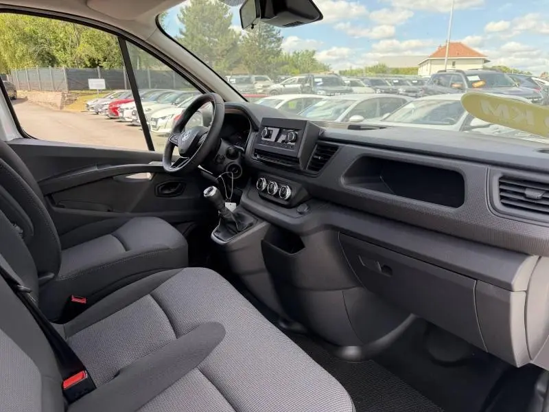 Vue intérieure côté conducteur du Renault Trafic Fourgon 2024, montrant le tableau de bord et la banquette avant en tissu gris.