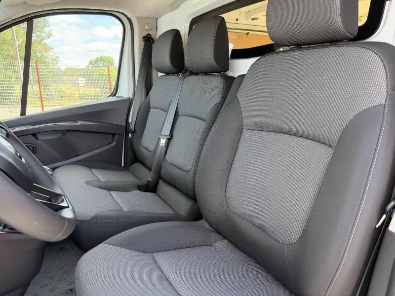 Vue intérieure côté conducteur du Renault Trafic Fourgon 2024, sièges tissu gris Kompo avec banquette 2 places monobloc.
