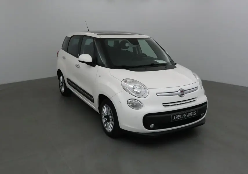 Fiat 500L blanc vue 3/4 avant droit dans un studio, avec toit ouvrant et jantes alliage visibles.
