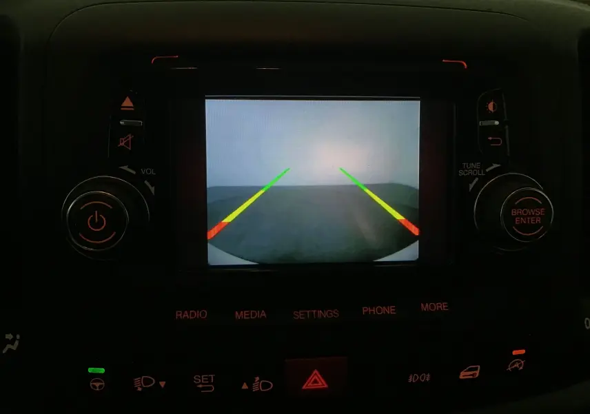 Écran de caméra de recul affichant les lignes de guidage dans l'habitacle sombre d'une Fiat 500L blanche 2015.