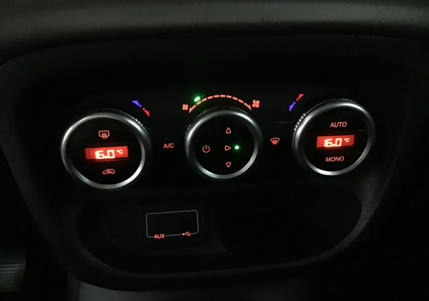 Gros plan sur les commandes de climatisation numérique rouge du tableau de bord d'une Fiat 500L blanche de 2015.
