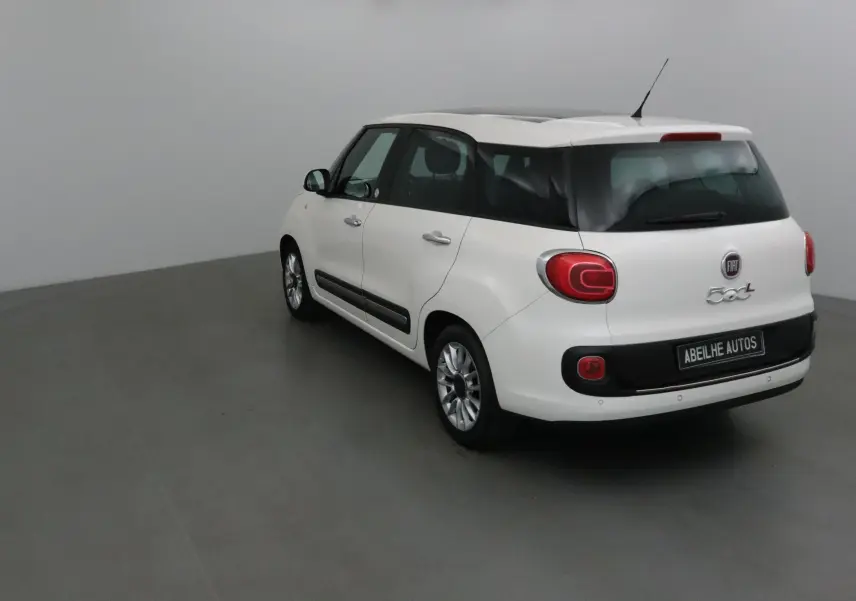 Fiat 500L blanc vue 3/4 arrière droit, avec lunette arrière surteintée et feux arrière arrondis distinctifs.