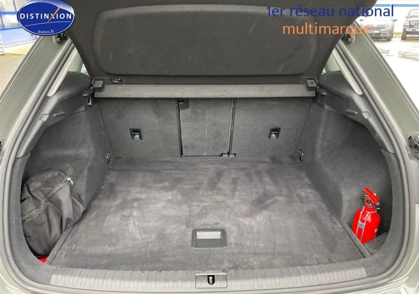 Coffre ouvert d'un Audi Q3 gris Chronos Metal, montrant un espace de chargement propre avec un extincteur rouge à droite.