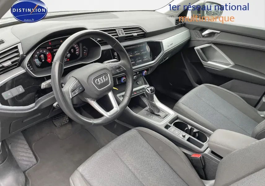 Intérieur de l'Audi Q3 2019 vu côté conducteur, tableau de bord numérique et sièges tissu gris visibles.