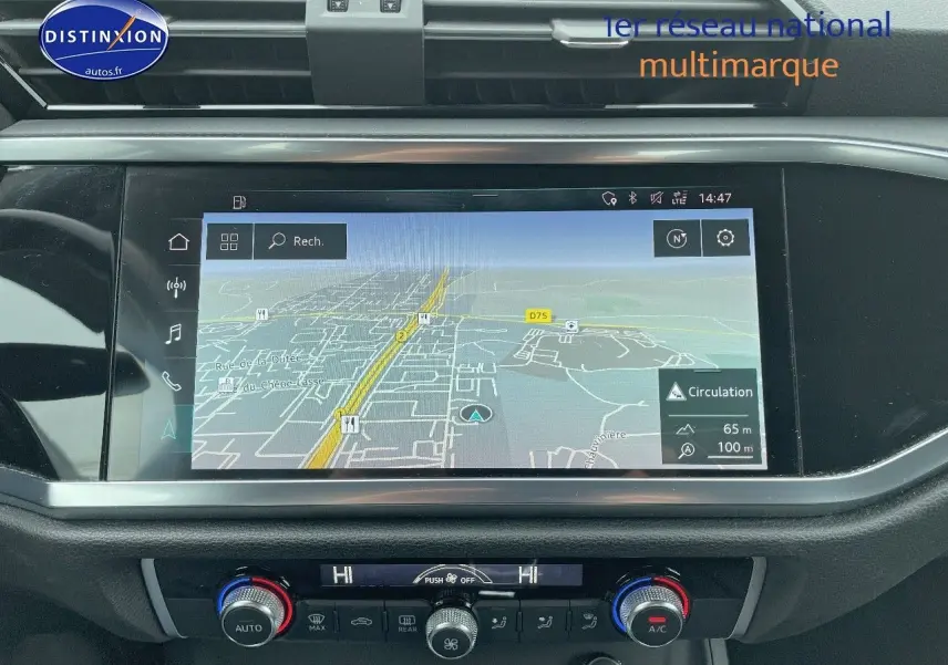 Vue rapprochée de l'écran tactile central et de la console de climatisation d'un Audi Q3 gris chronos métal de 2019.