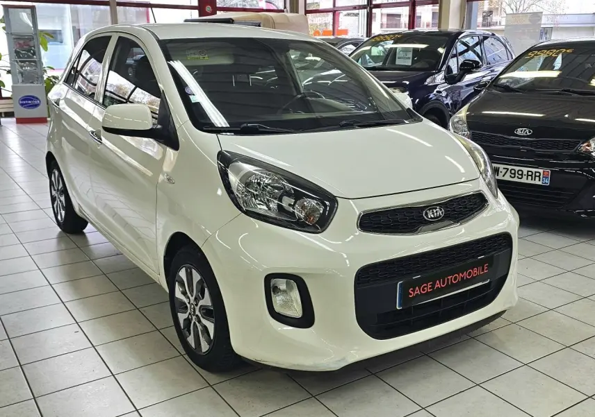 KIA Picanto II blanche vue en 3/4 avant droit dans un showroom avec calandre noire et jantes alliage.