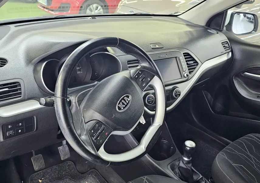 Intérieur de la KIA PICANTO blanche 2016, vue côté conducteur sur le tableau de bord et volant multifonction.