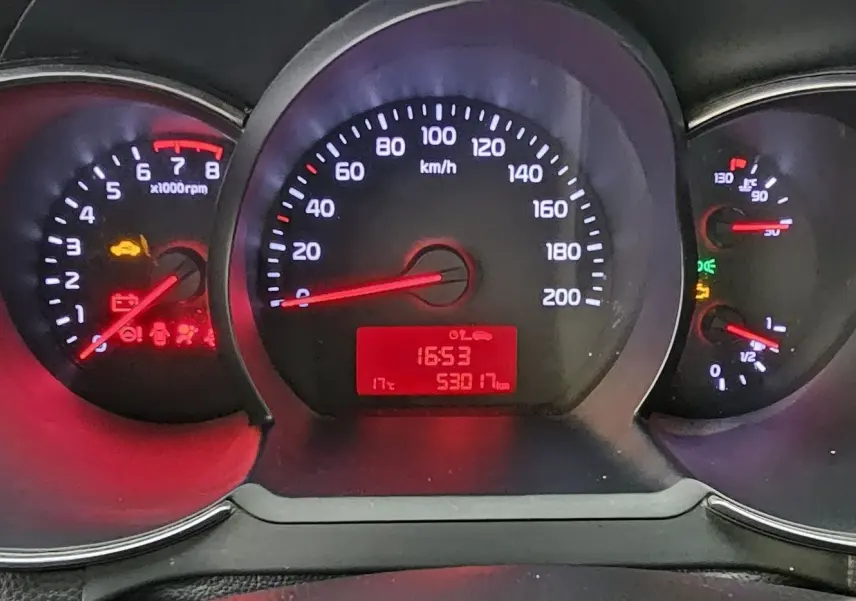 Tableau de bord de Kia Picanto 2016 avec compte-tours, compteur de vitesse et jauges éclairés en rouge et blanc.