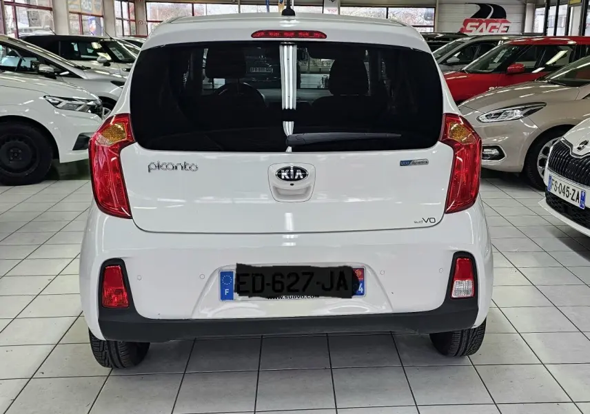 Vue arrière d'une KIA Picanto blanche de 2016, avec feux rouges et plaque d'immatriculation française visible.