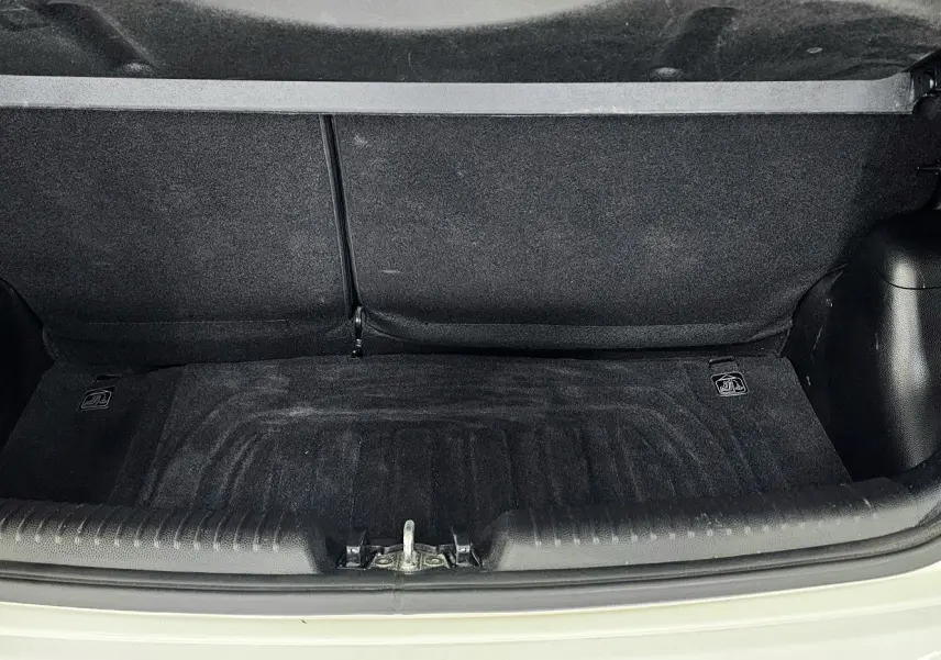 Coffre ouvert d'une KIA PICANTO II blanche de 2016, montrant l'espace de rangement intérieur propre et vide.