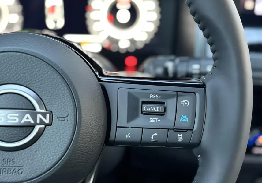 Gros plan sur le côté droit du volant cuir noir du Nissan Qashqai III avec commandes de régulateur et aides à la conduite.