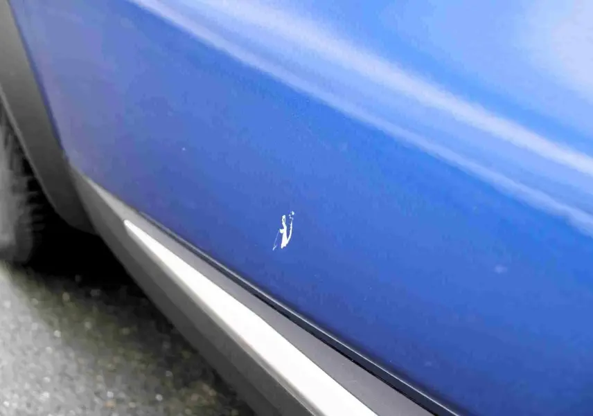 Gros plan sur la portière côté gauche d'une Renault Symbioz bleu iron metal avec une rayure visible.