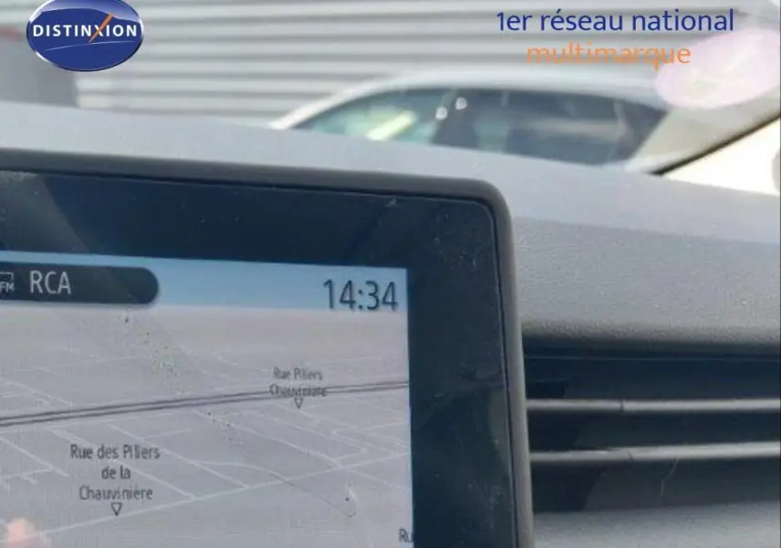 Vue intérieure du tableau de bord de la Renault Clio blanche 2021, avec écran de navigation et aérateurs visibles.