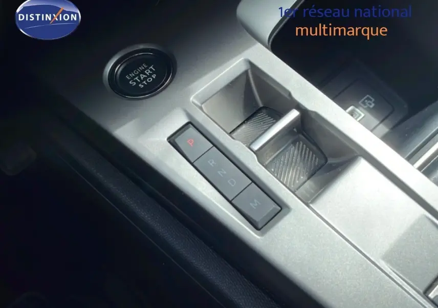 Gros plan sur la console centrale argentée de la Peugeot 308 SW Hybrid 2025 avec bouton start/stop et levier de boîte automatique.