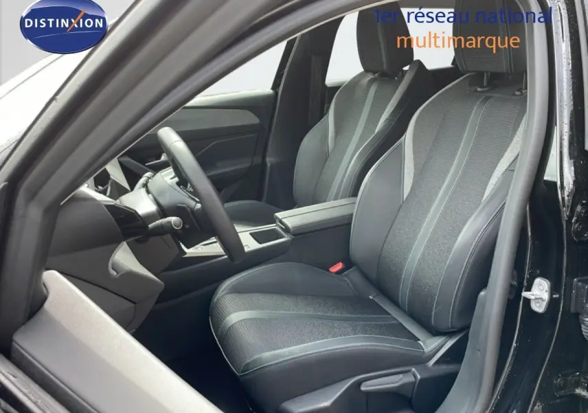 Vue intérieure côté conducteur de la Peugeot 308 SW Hybrid 145ch Allure 2025, sièges tissu et cuir noir métal.