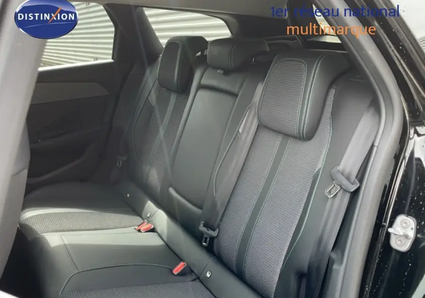Vue intérieure arrière côté droit du Peugeot 308 SW Hybrid 2025 noir métal, sièges tissu et cuir avec surpiqûres contrastées.