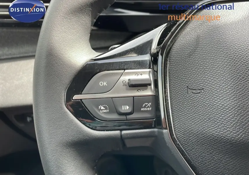 Gros plan sur les commandes gauche du volant cuir noir du Peugeot 308 SW Hybrid 2025, boutons de régulateur et assistant de conduite.