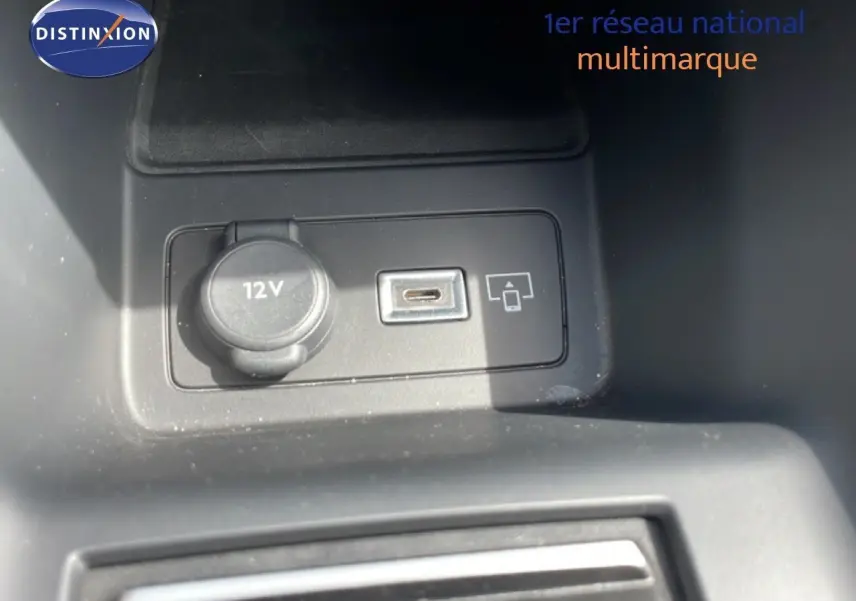 Vue rapprochée de la prise 12V et port USB dans l'habitacle noir d'une Peugeot 308 SW Hybrid 2025.