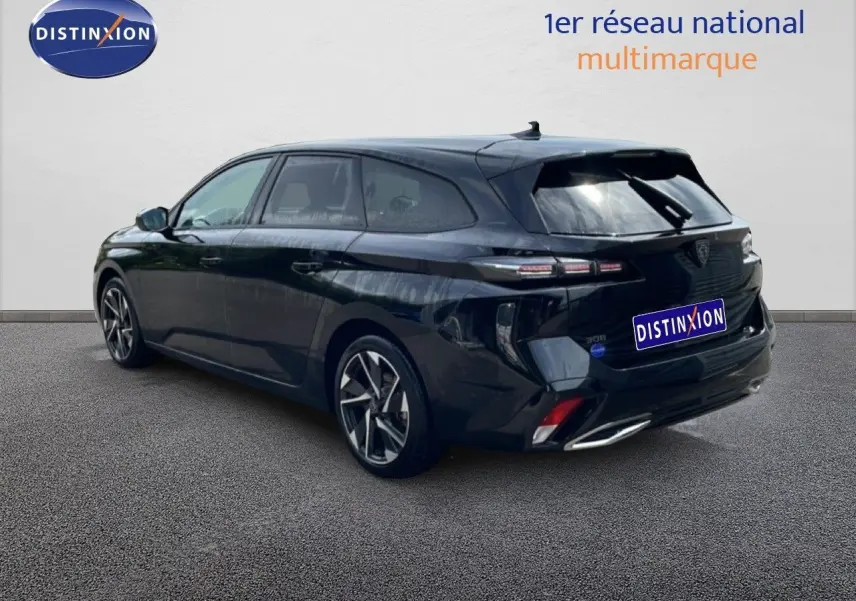 Vue 3/4 arrière droite d'une Peugeot 308 SW Hybrid noire métal avec jantes alliage et feux arrière LED distinctifs.
