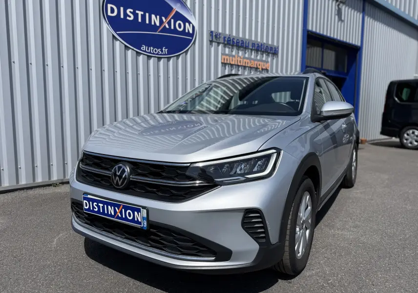 Volkswagen Taigo gris reflet d'argent métal en 3/4 avant droit, avec calandre noire et phares LED visibles.