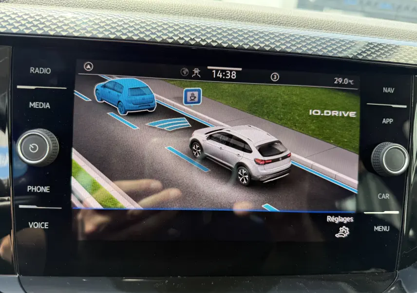 Affichage numérique intérieur montrant une Volkswagen Taigo gris reflet d'argent en vue 3/4 arrière droite avec assistance IQ.DRIVE active.