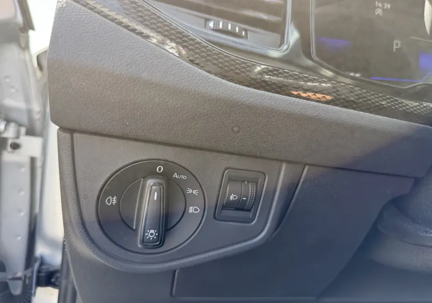 Gros plan sur le panneau de commande des phares à gauche du tableau de bord du Volkswagen Taigo gris reflet d'argent.