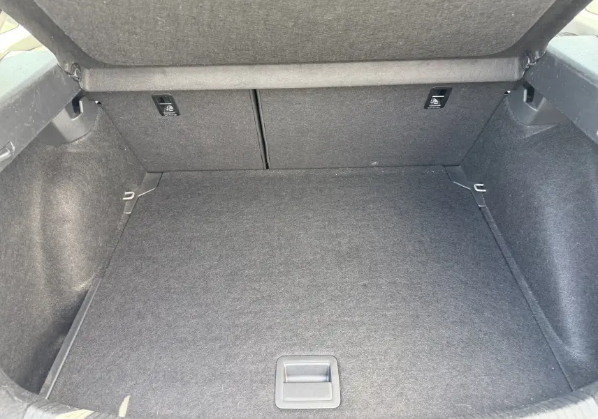 Vue intérieure du coffre spacieux et propre du Volkswagen Taigo gris reflet d'argent, avec revêtement tissu noir.